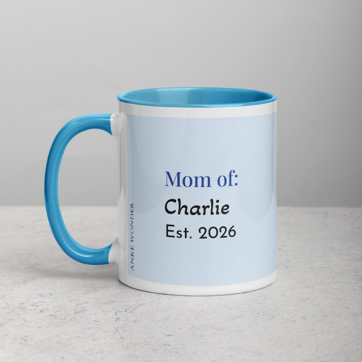 Backside of white and blue ceramic mug with a rblue handle and red interior displaying the words "Guinea Pig Mom" and an illustrated black and white guinea pig.