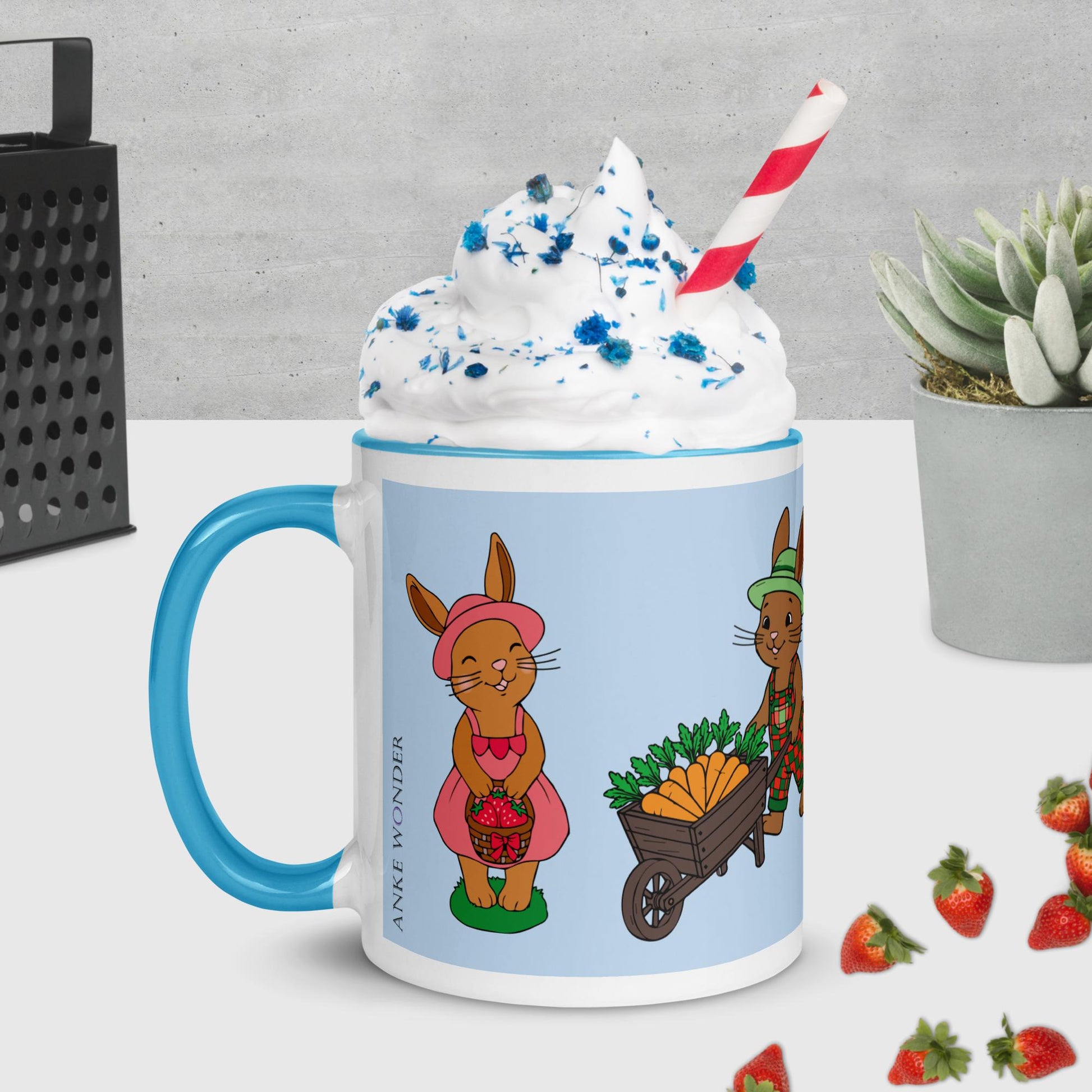 Mug with cartoon bunnies and blue handle, filled with a dessert-like drink.