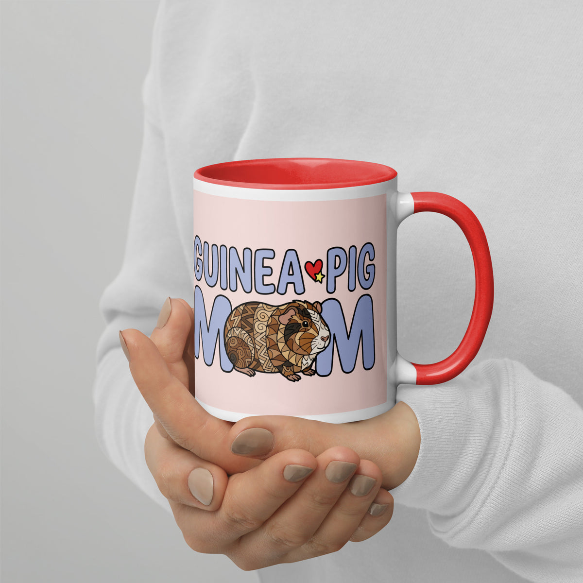 Front view of woman holding personalized Guinea Pig Mom ceramic mug featuring a cute brown and white guinea pig illustration with red handle and red interior, held in hands.