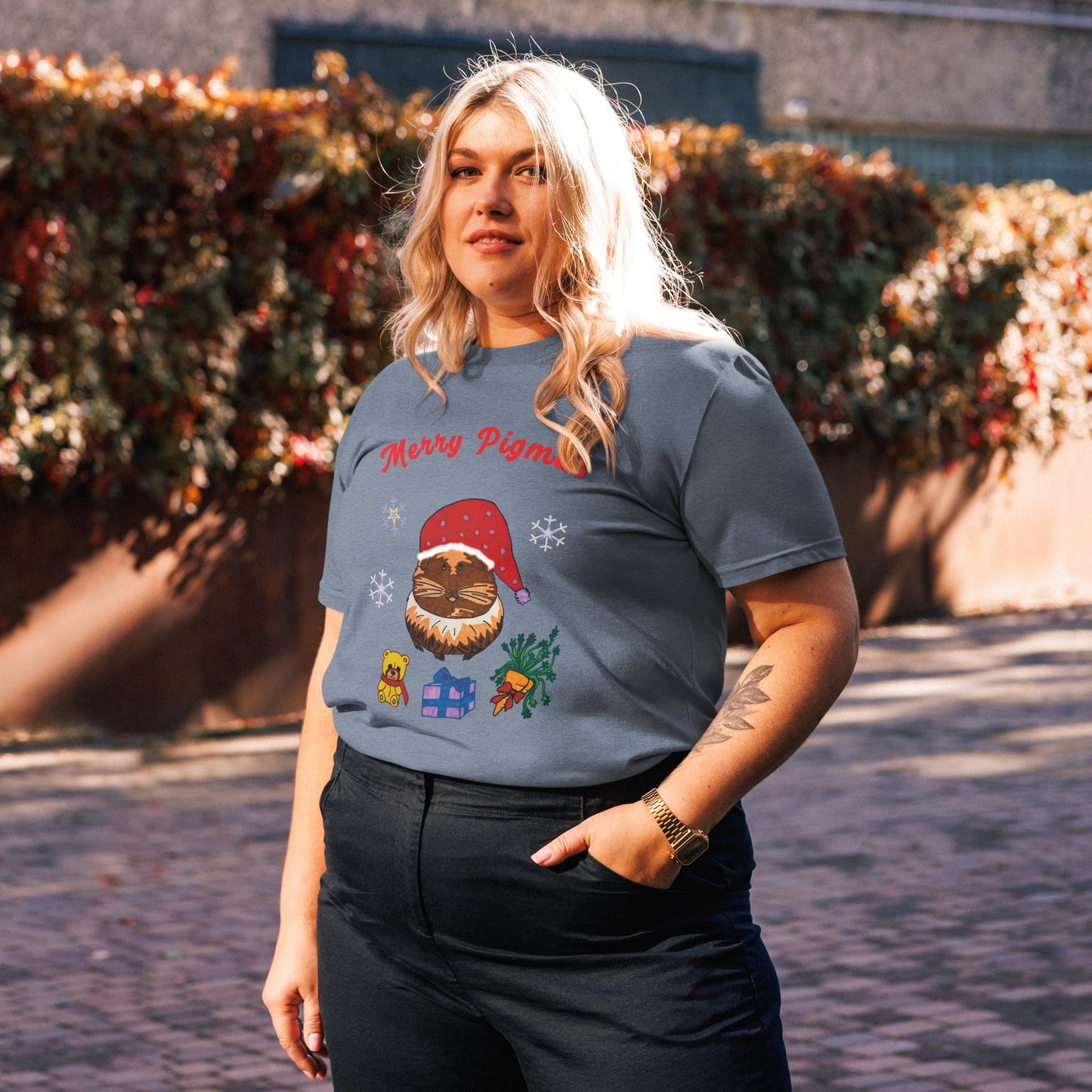 Woman wearing a festive t-shirt with a christmas guinea pig design and 'Merry Pigmas' text outdoors.