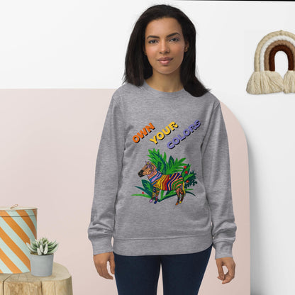 Woman wearing a gray sweatshirt with a colorful zebra design and text, standing against a light pink background.