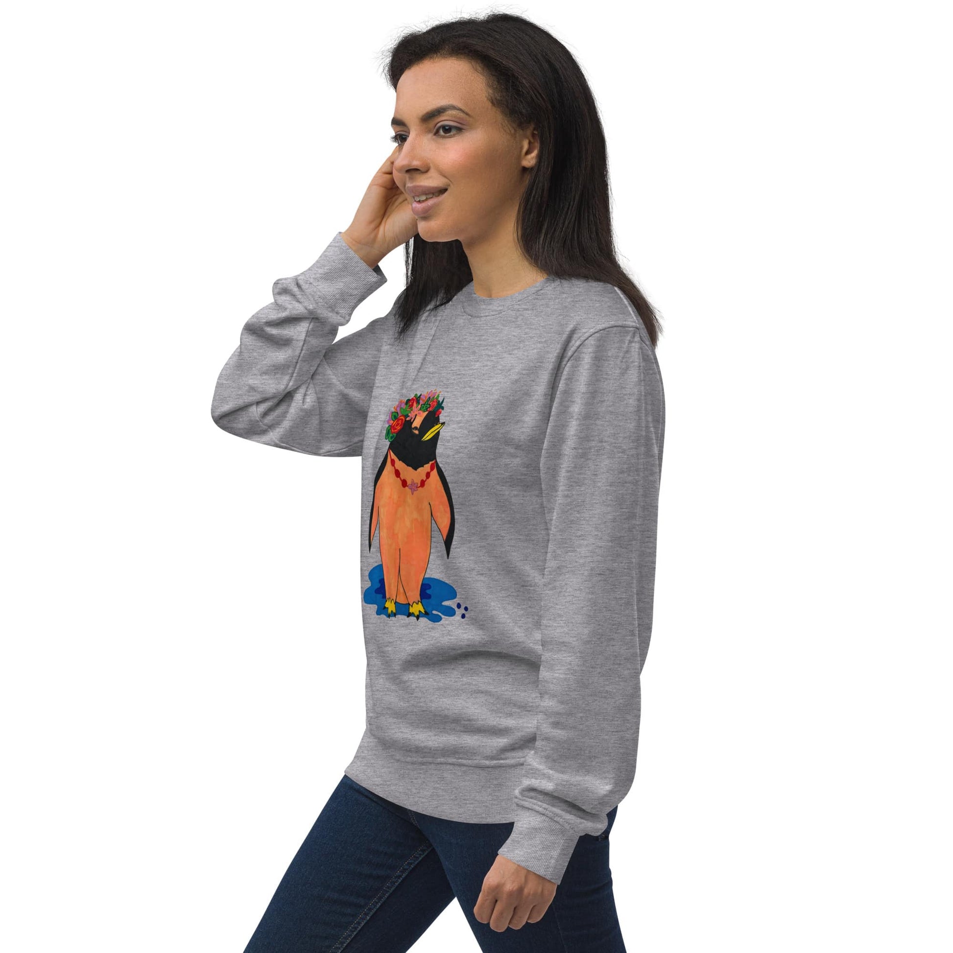 Woman wearing a gray sweatshirt with a colorful penguin design on a white background, standing to the side.