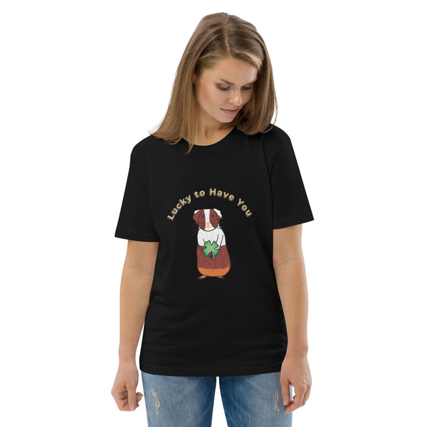 Woman wearing a black organic cotton t-shirt featuring a brown and white guinea pig holding a shamrock, with the text "Lucky to Have You" curved above the design.