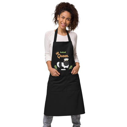 A woman models a black apron with a funny guinea pig chef print and the words 'Salad Queen' in vibrant colors.