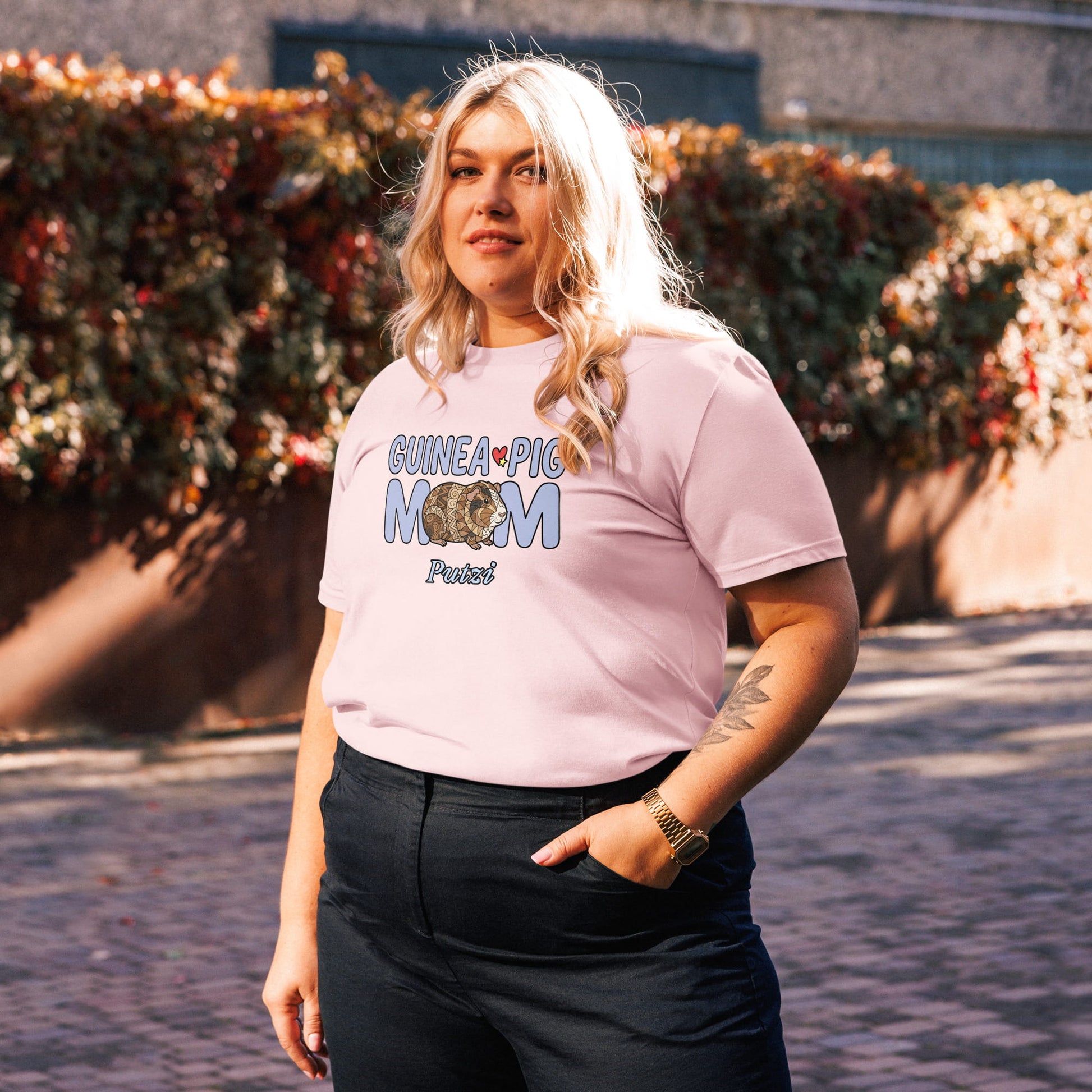 Person wearing a pink t-shirt with 'GUINEA PIG MOM' text, standing outdoors.