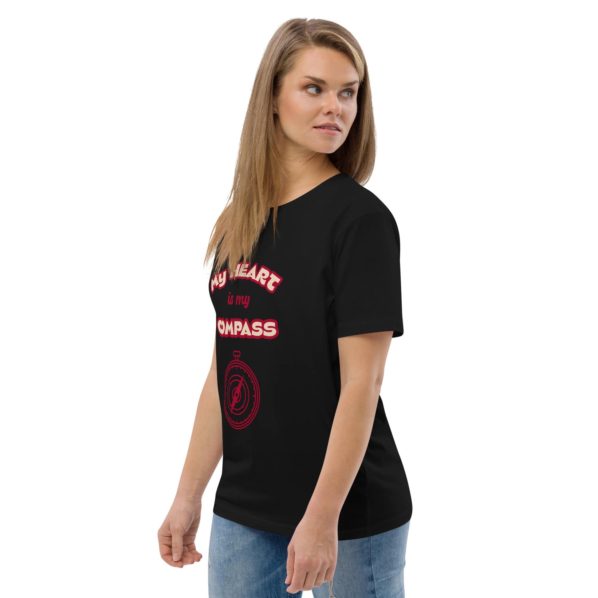 Front left view of woman wearing black organic cotton t-shirt with red ‘My Heart is My Compass’ design — casual spiritual clothing made from eco-conscious fabric.