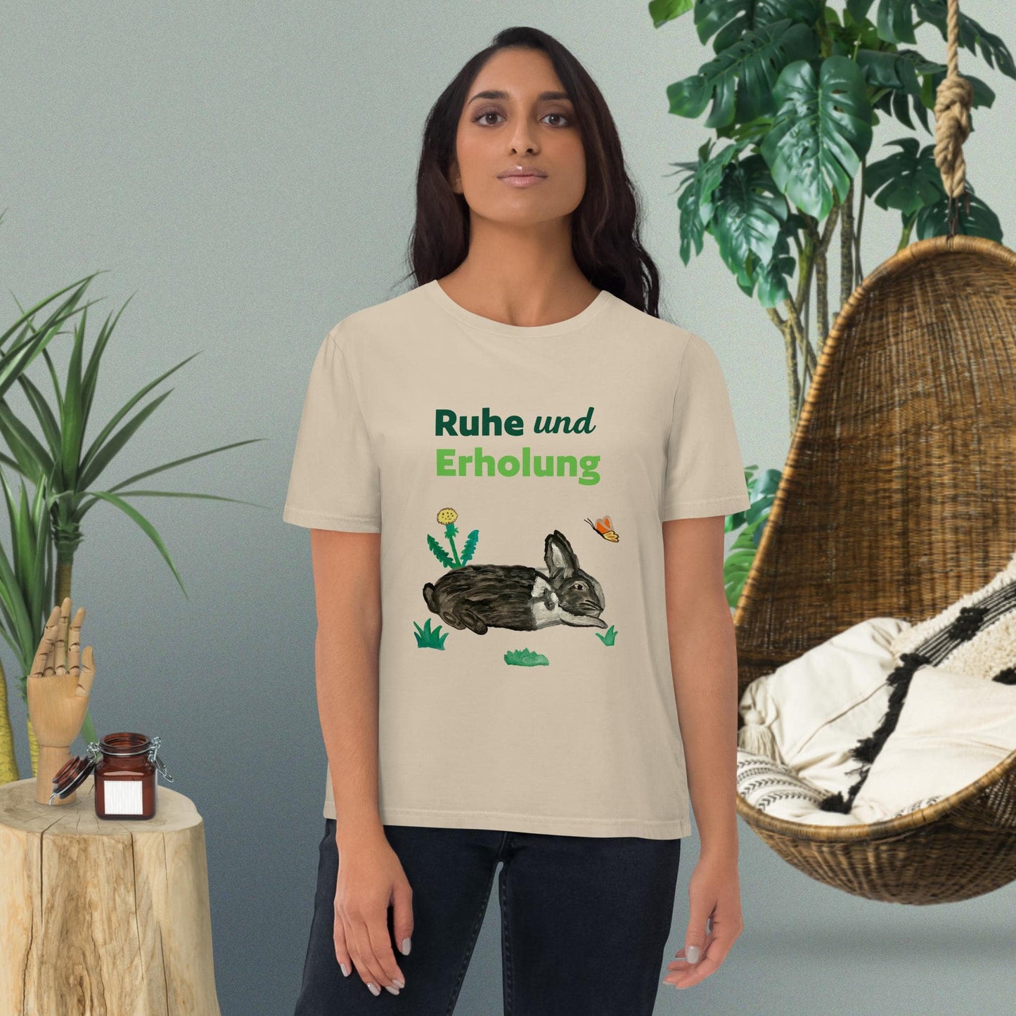Woman wearing "Ruhe & Erholung" t-shirt in desert dust, with rabbit and butterfly design by Anke Wonder.