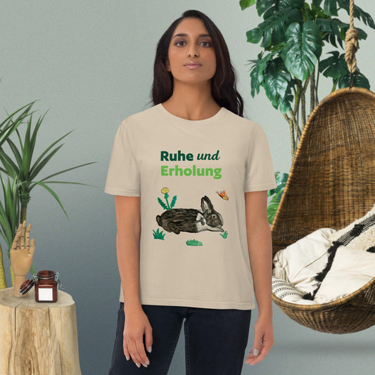 Woman wearing "Ruhe & Erholung" t-shirt in desert dust, with rabbit and butterfly design by Anke Wonder.