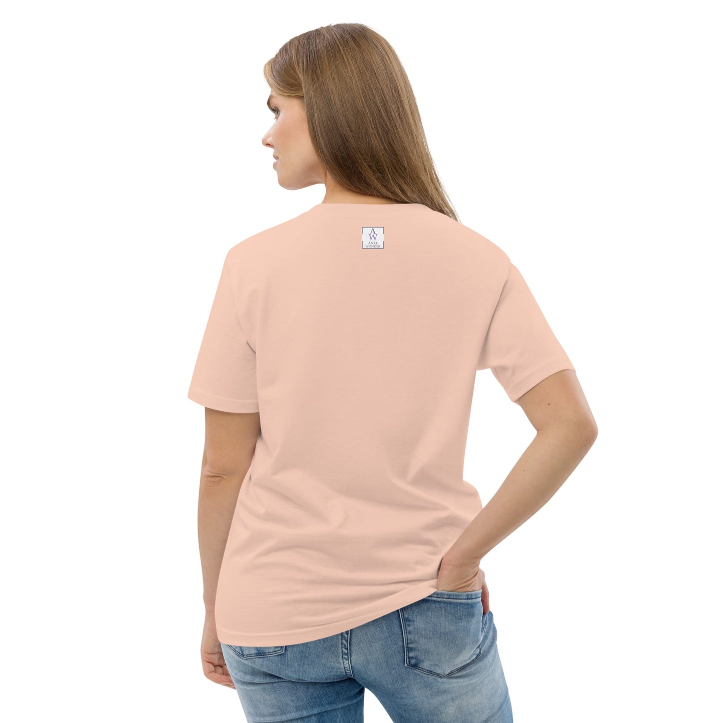 Back side of woman wearing a light peach t-shirt with a small Anke Wonder logo on the back, standing against a white background.