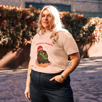 Side view of woman wearing a peach t-shirt with a bunny graphic design and words 'Christmas Snuggles' outdoors