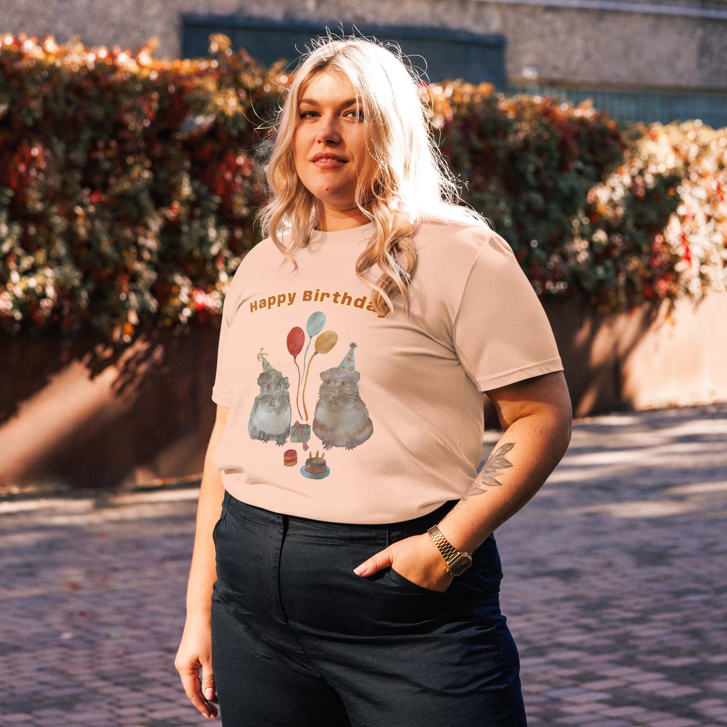Side view of woman wearing a peach t-shirt with a with guinea pig drawing outdoors.