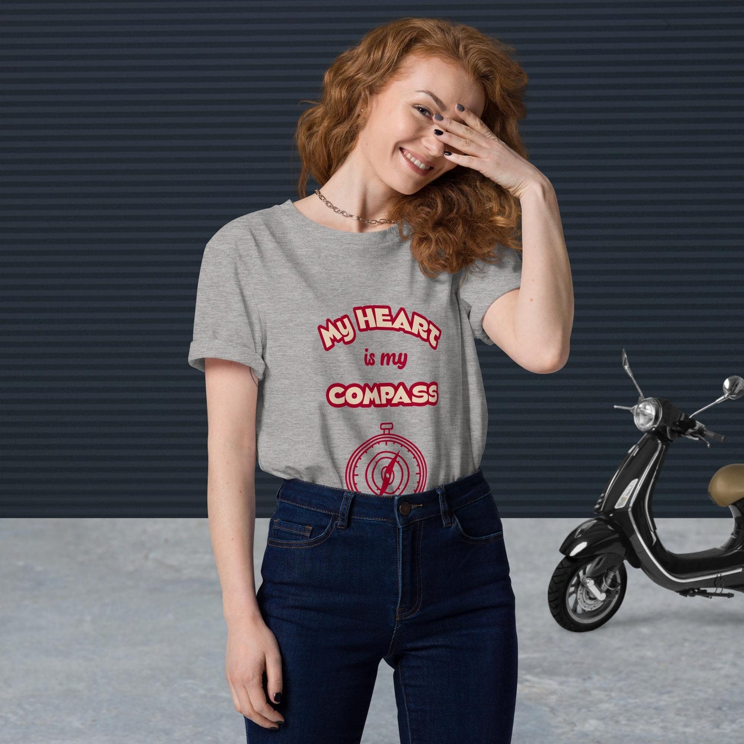 Front view of woman wearing tucked-in heather grey organic cotton t-shirt with red 'My Heart is My Compass' design — stylish and sustainable spiritual clothing.