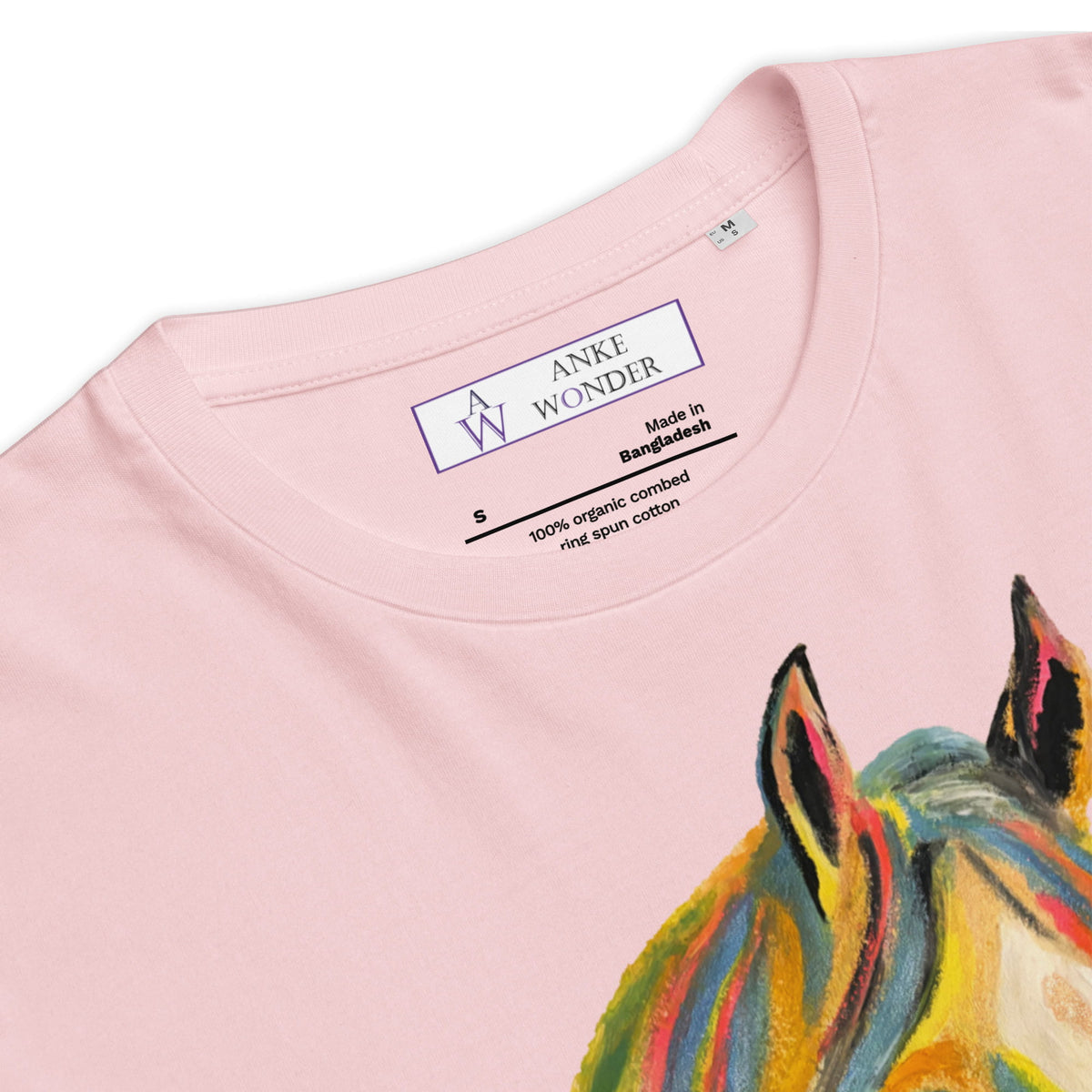 Close-up of a light pink t-shirt showing the inner neck label with 'ANKE WONDER' and a colorful painted horse design on the front.