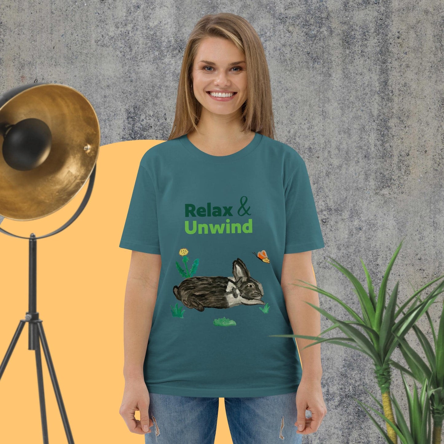 Woman wearing organic cotton t-shirt in stargazer color with hand-painted black-and-white rabbit, butterfly, greens, and "Relax & Unwind" text — front view.