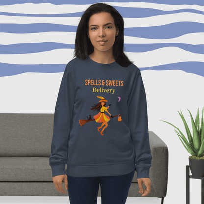 Woman wearing a navy sweatshirt with 'Spells & Sweets Delivery' Witch design in a living room setting.