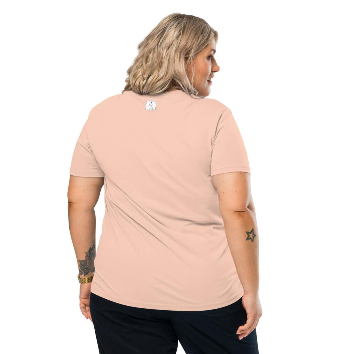 Back view of woman wearing a peach t-shirt with the Anke Wonder logo on a white background