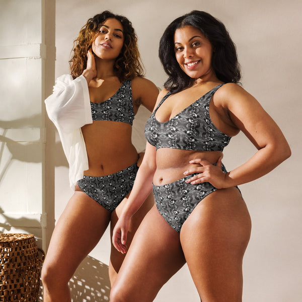 Two women wearing matching black and white bird patterned swimsuits standing side by side.