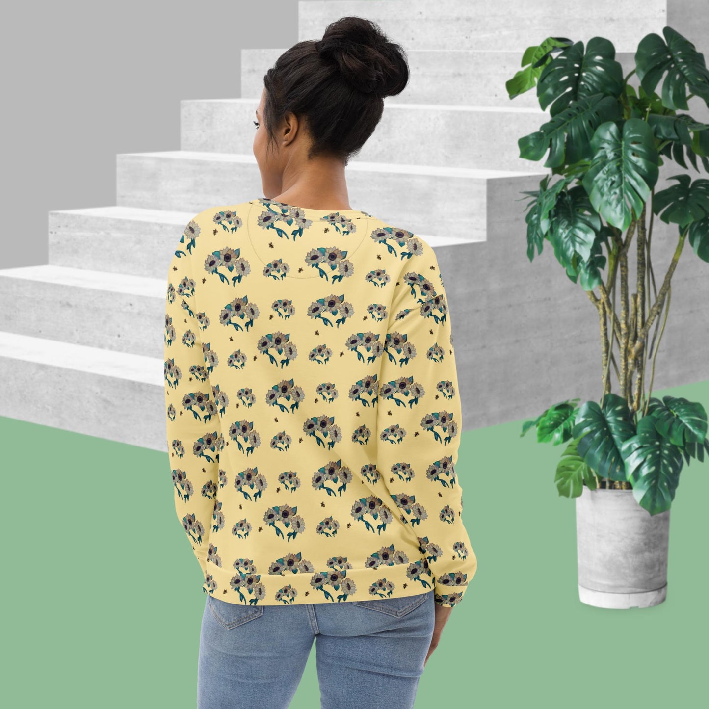 Backside of woman wearing a yellow floral-patterned shirt standing on a staircase with a plant in the foreground.