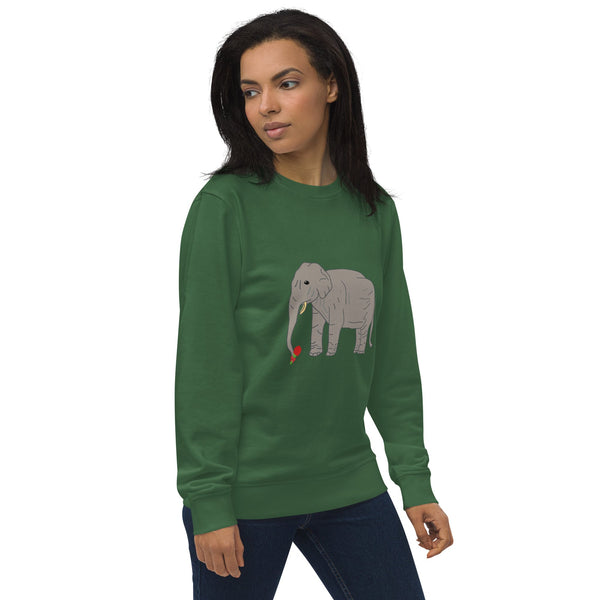 Side view of a woman wearing a green organic sweatshirt, showcasing the relaxed fit and sustainable fabric. The design features an illustration of an elephant holding a red rose on the front.