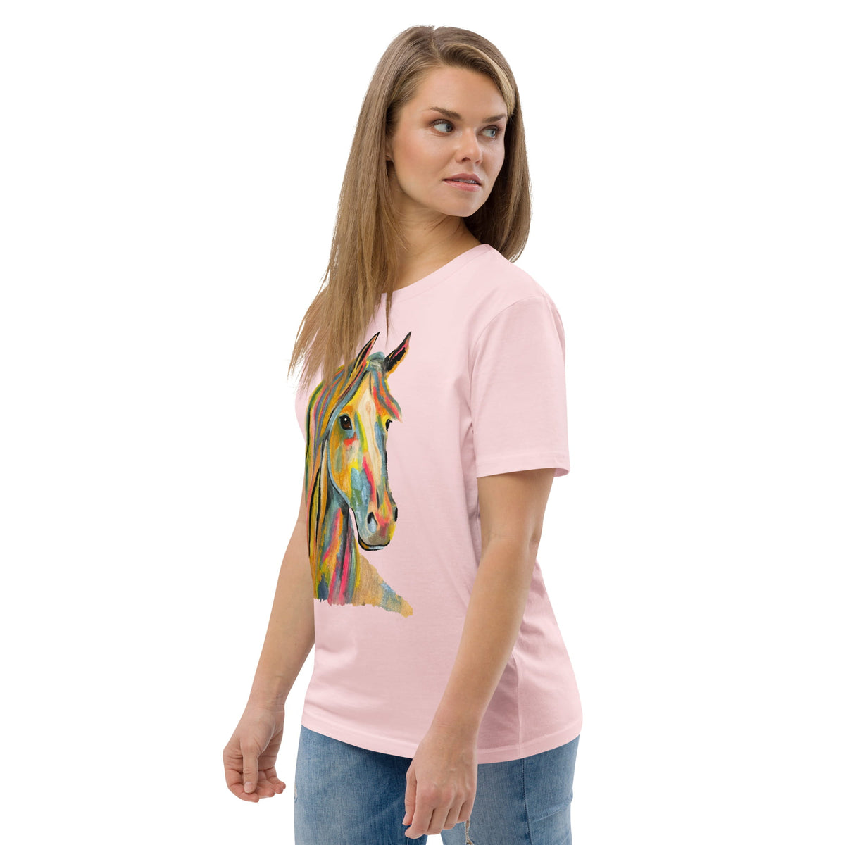 A woman modeling a light pink short-sleeve t-shirt with a colorful watercolor-style horse graphic on the front, paired with blue jeans against a plain white background.
