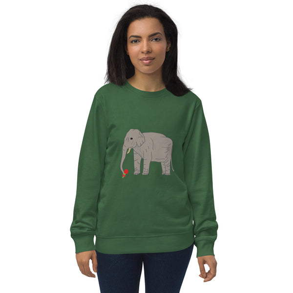 Woman wearing a green organic sweatshirt featuring an illustration of an elephant holding a red rose with its trunk. The design combines gentle elegance and eco-conscious fashion.