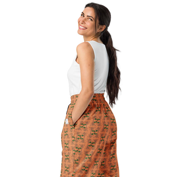 Right back view of a woman wearing orange joggers with a seamless oak vine and acorn print, highlighting the eco-friendly wide-leg style.