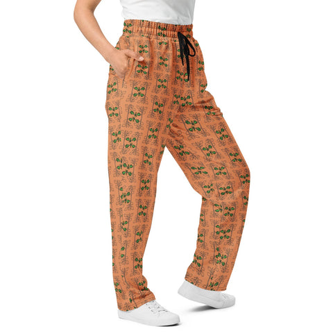 Front close-up view of a woman modeling wide-leg orange joggers, showcasing the intricate oak vine and acorn pattern and relaxed fit