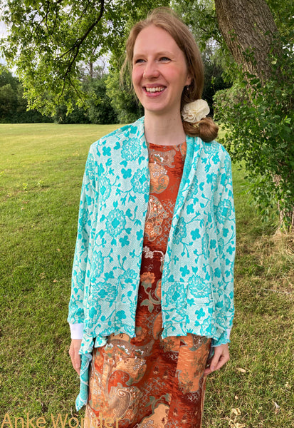 Women's mint-green cardigan with white cuffs and floral pattern shown open from the front.