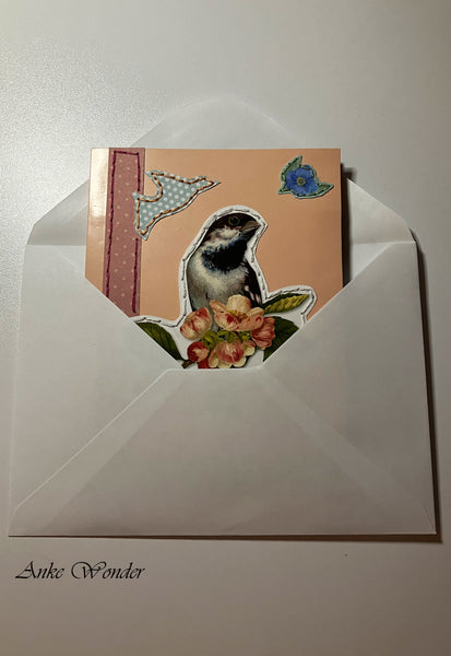 Handmade card with colorful birds and pink flowers in a white envelope.